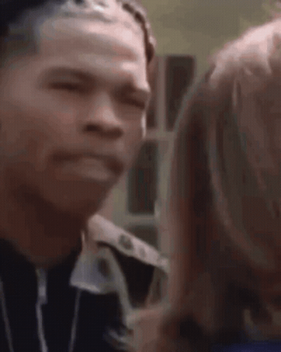 A Man And A Woman Are Looking At Each Other And The Man Is Making A Face . GIF