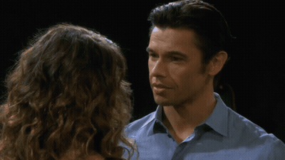 A Man And A Woman Are Looking At Each Other And The Man Is Wearing A Blue Shirt GIF