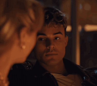 A Man And A Woman Are Looking At Each Other And The Man Is Wearing A Leather Jacket GIF