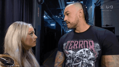 A Man And A Woman Are Looking At Each Other And The Man Is Wearing A Terror Shirt GIF