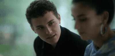 A Man And A Woman Are Looking At Each Other And The Man Is Wearing Earrings . GIF