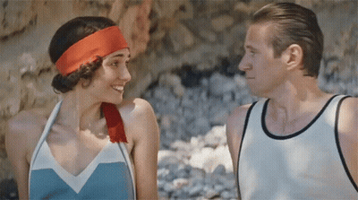 A Man And A Woman Are Looking At Each Other And The Woman Has A Red Headband On GIF