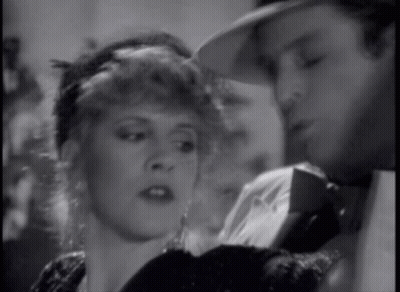 A Man And A Woman Are Looking At Each Other In A Black And White Photo GIF