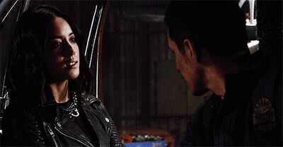 A Man And A Woman Are Looking At Each Other In A Car . The Woman Is Wearing A Leather Jacket . GIF