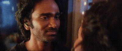 A Man And A Woman Are Looking At Each Other In A Dark Room . GIF