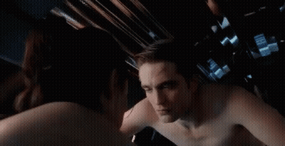 A Man And A Woman Are Looking At Each Other In A Mirror . GIF