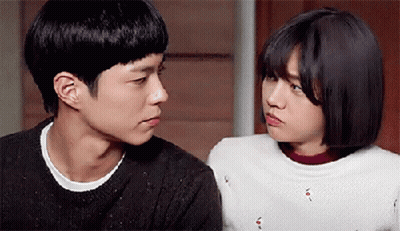 A Man And A Woman Are Looking At Each Other In A Room . GIF
