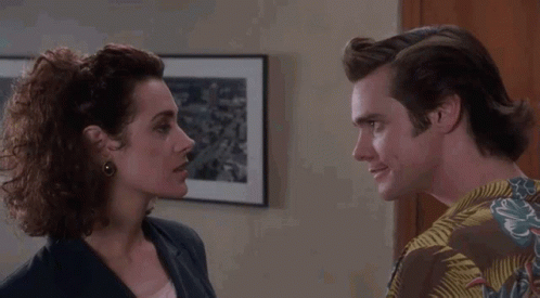 A Man And A Woman Are Looking At Each Other In A Room With A Picture On The Wall . GIF