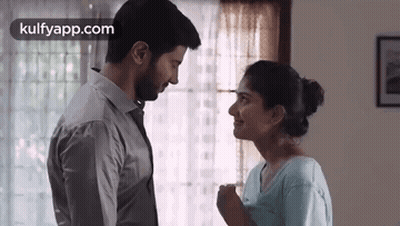 A Man And A Woman Are Looking At Each Other In Front Of A Window . GIF