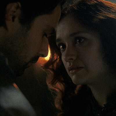 A Man And A Woman Are Looking At Each Other In The Dark GIF