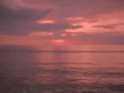 A Man And A Woman Are Looking At Each Other On A Beach At Sunset GIF