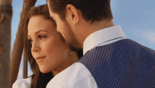 A Man And A Woman Are Looking At Each Other With A Blue Sky In The Background GIF