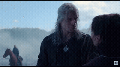 A Man And A Woman Are Looking At Each Other With A Horse In The Background GIF