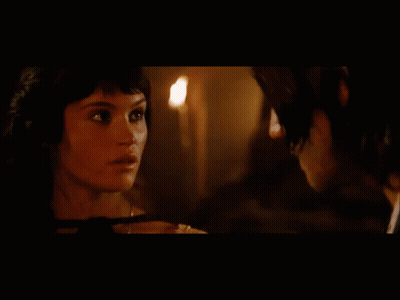 A Man And A Woman Are Looking At Each Other With A Mountain In The Background GIF