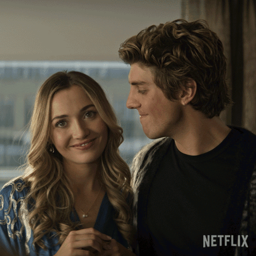 A Man And A Woman Are Looking At Each Other With A Netflix Logo In The Background GIF