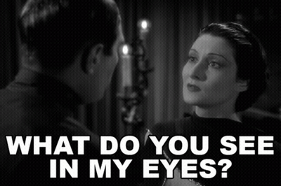 A Man And A Woman Are Looking At Each Other With The Words What Do You See In My Eyes Above Them GIF