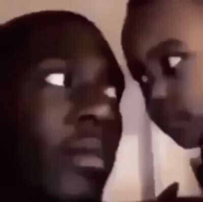 A Man And A Woman Are Looking At Each Other With Their Eyes Wide Open . GIF