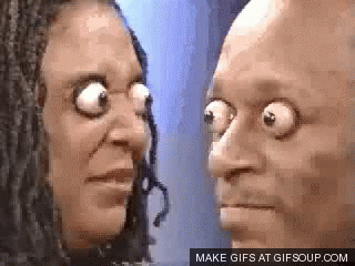 A Man And A Woman Are Looking At Each Other With Their Eyes Wide Open . GIF