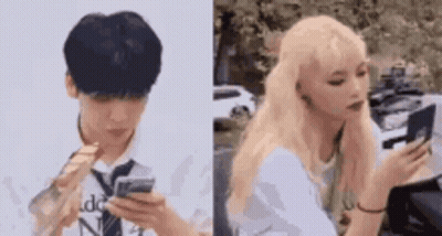 A Man And A Woman Are Looking At Their Phones . The Man Is Wearing A Tie And The Woman Is Blonde . GIF