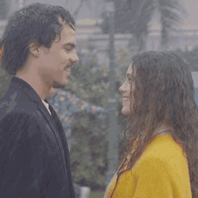 A Man And A Woman Are Looking Into Each Other 'S Eyes And The Woman Is Wearing A Yellow Sweater GIF
