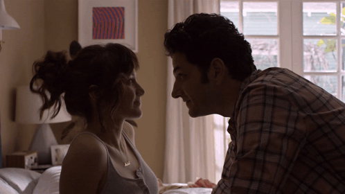 A Man And A Woman Are Looking Into Each Other 'S Eyes In A Bedroom GIF