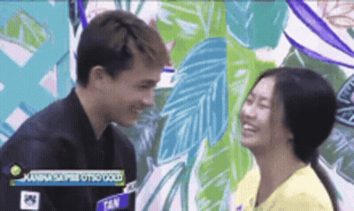 A Man And A Woman Are Looking Into Each Other 'S Eyes In Front Of A Mural . GIF