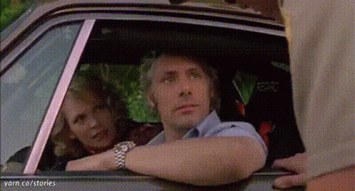 A Man And A Woman Are Looking Out The Window Of A Car . GIF