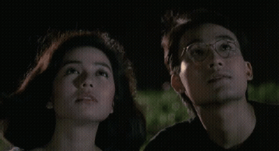 A Man And A Woman Are Looking Up At The Sky Together GIF