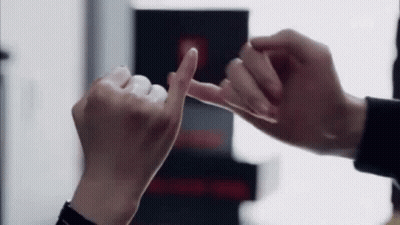 A Man And A Woman Are Making A Pinkie Promise With Their Fingers . GIF