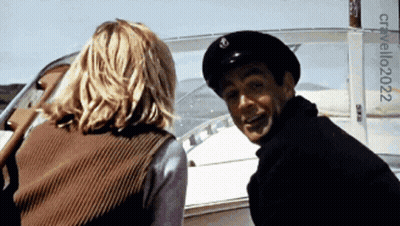 A Man And A Woman Are On A Boat With A Sign That Says Cristallo2022 On It GIF