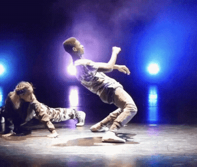 A Man And A Woman Are Performing On A Stage With Blue Lights Behind Them GIF