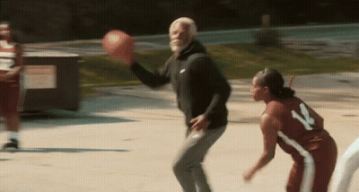 A Man And A Woman Are Playing Basketball On A Court And The Man Is Throwing The Ball To The Woman . GIF