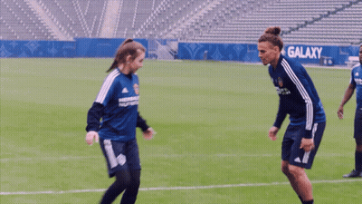 A Man And A Woman Are Playing Soccer And The Woman Is Wearing A Shirt That Says Herbalife On It GIF
