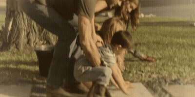 A Man And A Woman Are Playing With A Child On The Sidewalk GIF