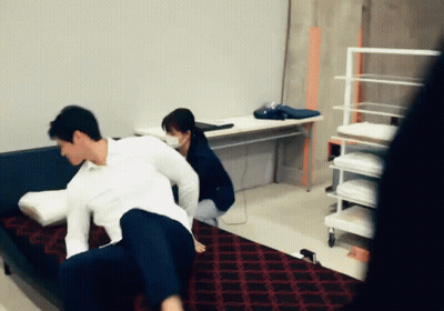 A Man And A Woman Are Playing With Pillows On A Couch In A Room GIF