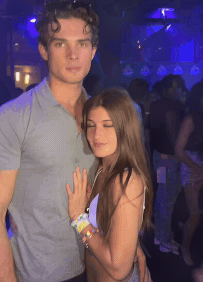 A Man And A Woman Are Posing For A Photo In A Club GIF
