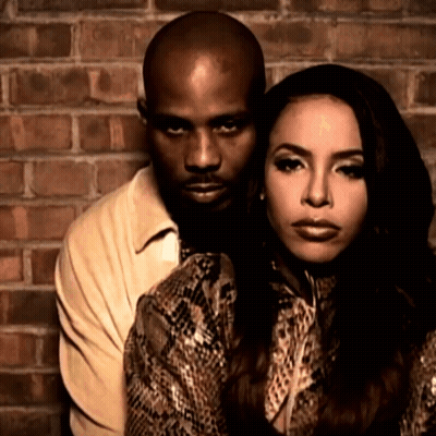 A Man And A Woman Are Posing For A Picture Against A Brick Wall GIF