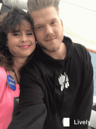 A Man And A Woman Are Posing For A Picture And The Man Is Wearing A Black Hoodie With The Word Scott On It GIF