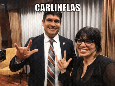 A Man And A Woman Are Posing For A Picture And The Man Is Wearing A Suit And Tie And The Woman Is Wearing Glasses GIF