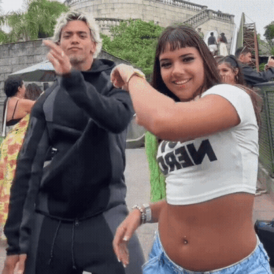 A Man And A Woman Are Posing For A Picture And The Woman Is Wearing A Crop Top That Says ' Mebo ' GIF