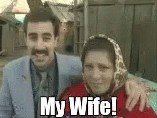 A Man And A Woman Are Posing For A Picture And The Woman Is Wearing A Scarf And The Man Is Smiling . GIF