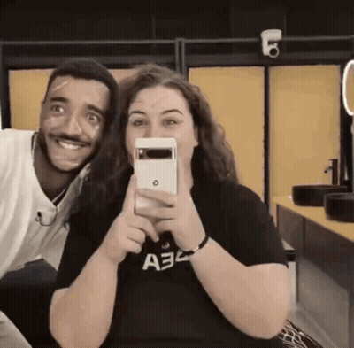 A Man And A Woman Are Posing For A Picture And The Woman Is Wearing A Shirt That Says A32 On It GIF