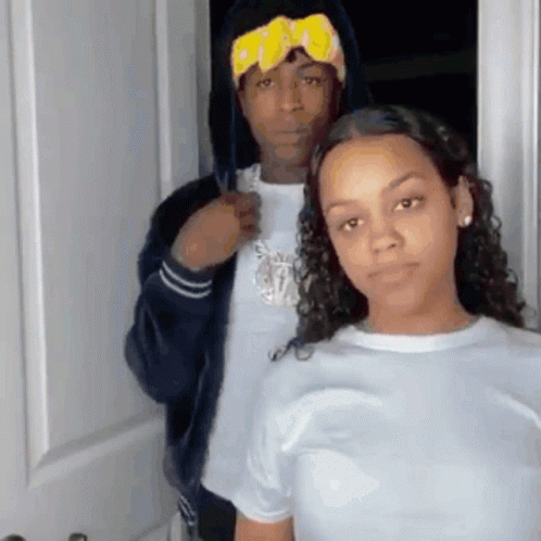 A Man And A Woman Are Posing For A Picture In Front Of A Door . GIF