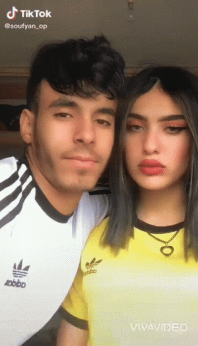 A Man And A Woman Are Posing For A Picture . The Woman Is Wearing A Yellow Adidas Shirt . GIF