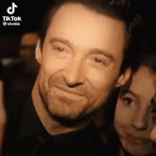 A Man And A Woman Are Posing For A Picture Together And The Man Is Smiling . GIF