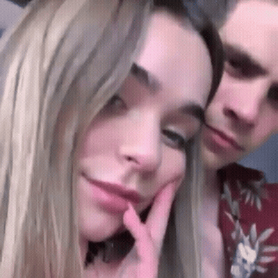 A Man And A Woman Are Posing For A Picture Together . The Woman Is Touching Her Face . GIF