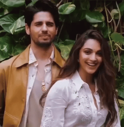 A Man And A Woman Are Posing For A Picture While Standing Next To Each Other . GIF