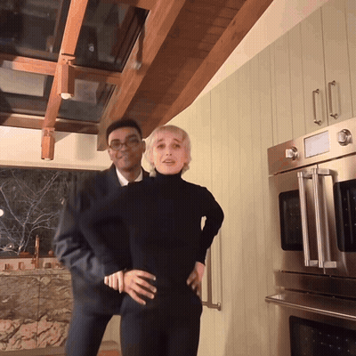 A Man And A Woman Are Posing In A Kitchen GIF