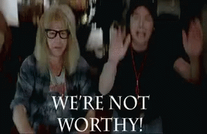 A Man And A Woman Are Raising Their Arms In The Air With The Words `` We 'Re Not Worthy '' Behind Them . GIF