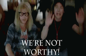 A Man And A Woman Are Raising Their Arms In The Air With The Words `` We 'Re Not Worthy '' Behind Them . GIF